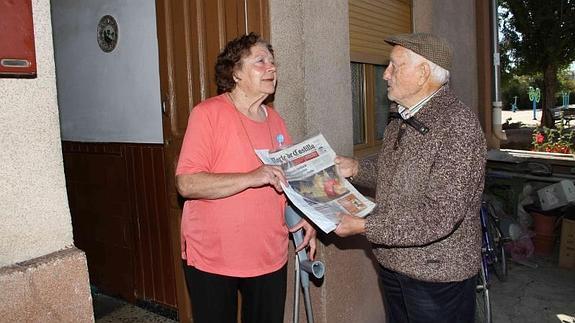 Consuelo Arratia entrega un periódico a Gregorio Escudero, vecino de Castroverde.