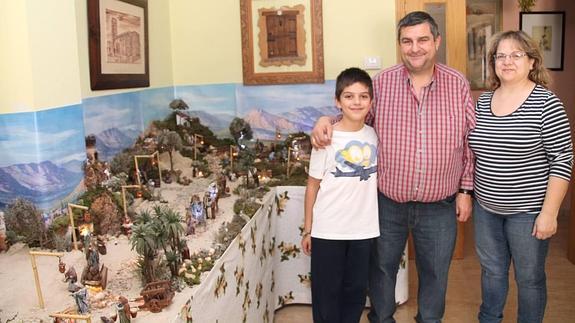 Alonso Herguedas Tejo y sus padres posan junto al belén que se alzó con el primer premio. 