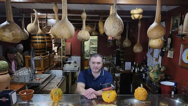 Alfonso Moreno, en el mostrador de su mesón Casti, con decenas de calabazas cedidas por los clientes colgadas del techo 