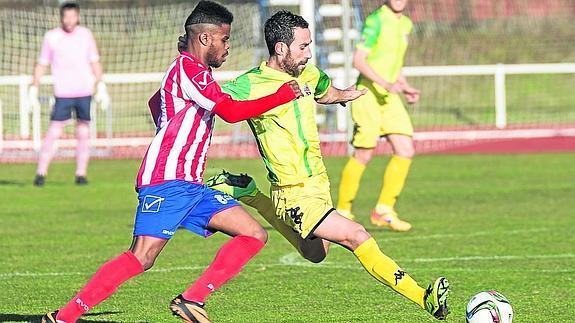 Chuchi Jorques golpea el balón perseguido por Aleixo. 