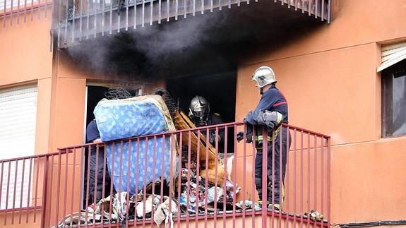 Los bomberos sacan colchones de la casa.