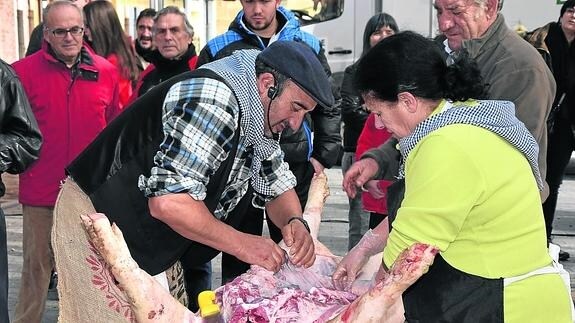 El público observa las tareas de destazado del cerdo, en la fiesta de la matanza de Velilla.