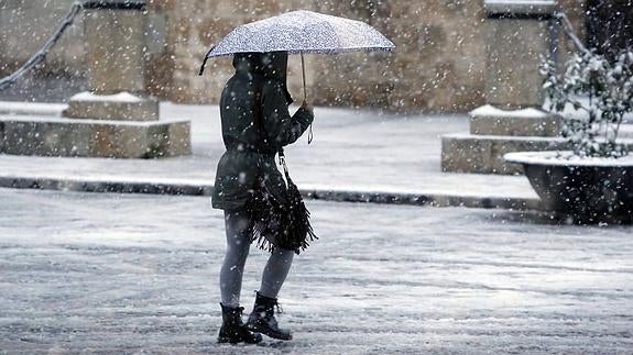 Una mujer camina bajo la nieve en León.