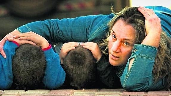 Una mujer tumbada en el suelo protege a sus hijos durante una alarma de atentado.