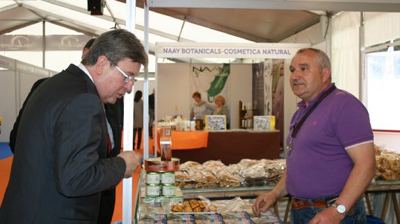 Un expositor local atiende al que fuera presidente de las Cortes y Consejero, José Manuel Fernández Santiago. F.G.MURIEL