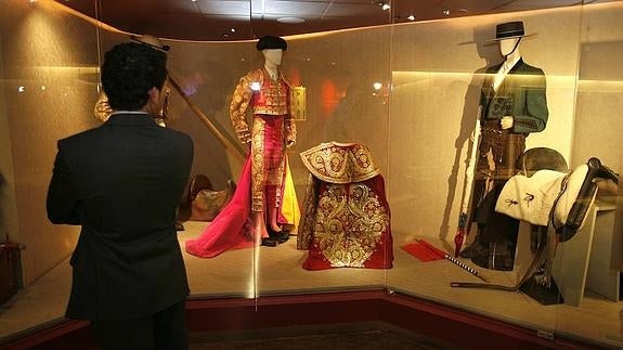 Un visitnte observa varios trajes expuestos en las vitrinas. 