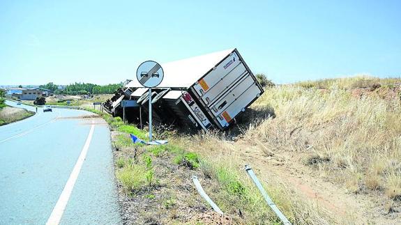 El camión volcado en la cuneta tras llevarse una señal. 