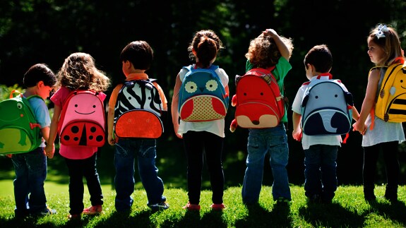 Siete niños en fila con diferentes mochilas