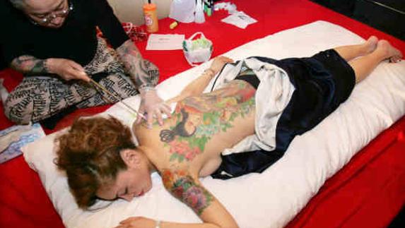 Un artista japonés Horiyoshi realizando tatuajes temporales en un club de Tokyo, Japón