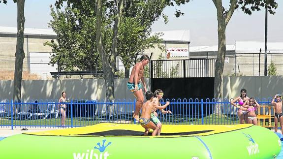 Tres niños saltan en uno de los hinchables colocados en la piscina municipal de Tejares.