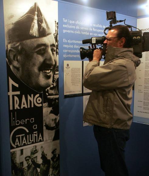 Un cámara toma imágenes de un cartel franquista en una exposición sobre los papeles del Archivo en Barcelona.