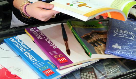 Una mujer hojea unos libros de texto en una anterior 'vuelta al cole'. 