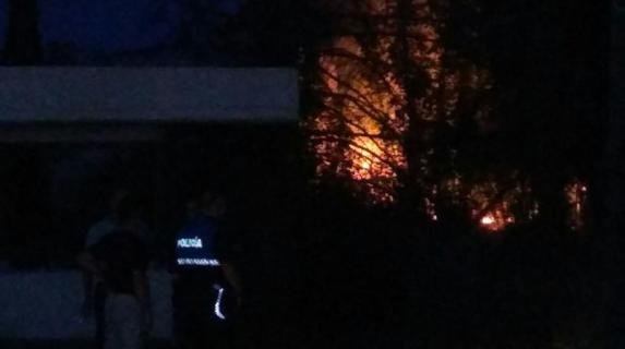 Un agente de la Policía Local y varios vecinos junto al incendio.