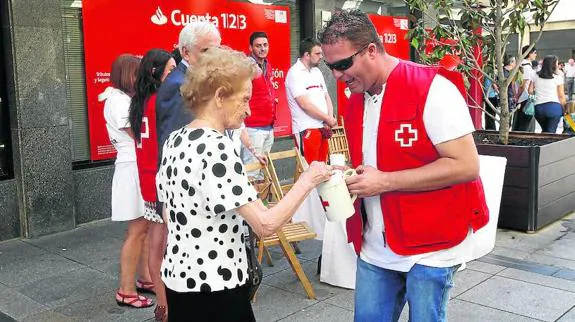 Una mujer mete el dinero n una de las huchas de la Cruz Roja. 