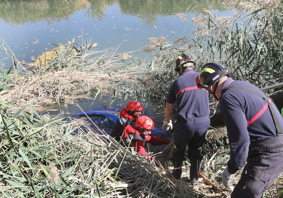 Los bomberos trabajan en la retirada del vehículo del agua. 