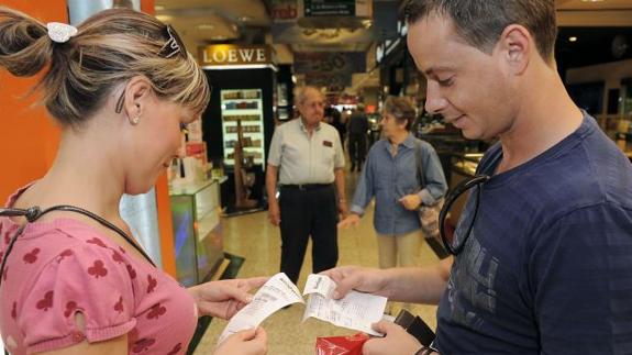 Dos jóvenes revisan sus tickets después de realizar una compra.