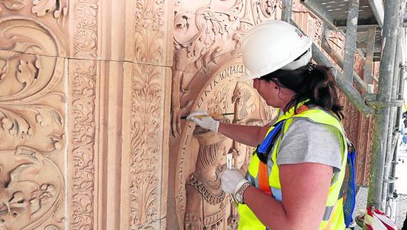 Una restauradora trabaja en la zona de la fachada donde luce el medallón de los Reyes Católicos.