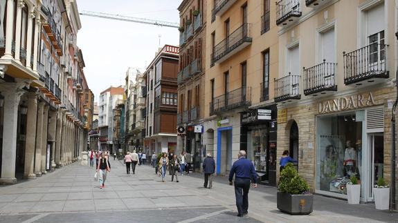 Algunas personas caminan con bolsas de compras por la Calle Mayor