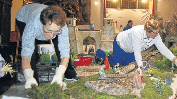 Dos mujeres de la asociación trabajan en el montaje del belén de Santa Clara. M. Rico