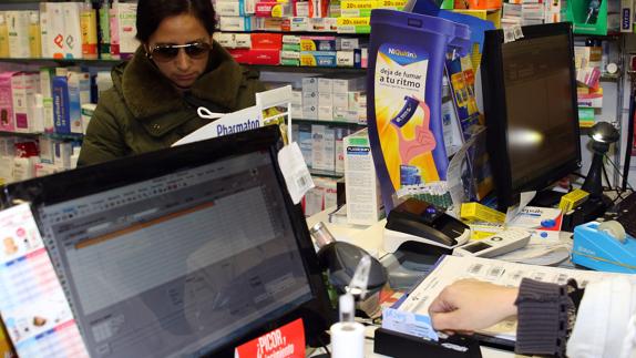 Una mujer solicita sus medicamentos en una farmacia de la capital mediante la receta electrónica con su tarjeta sanitaria. Antonio de Torre