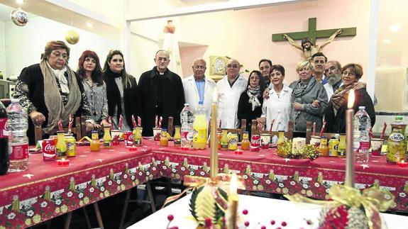 Personal voluntario del Banco de Alimentos posa junto a Carlos López, obispo de Salamanca antes del comienzo de la cena de Nochebuena. 