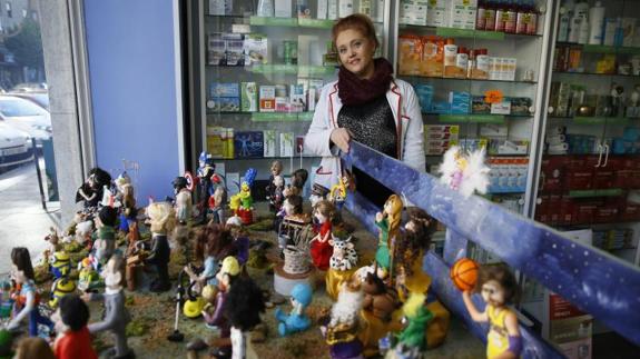 Regina, con las figuras quE componen el Belén de figuras de famosos de la farmacia de la calle Torrecilla.
