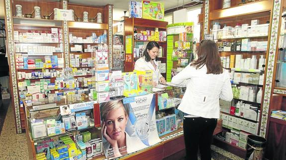 Una mujer es atendida en una farmacia de la Calle Mayor de Palencia.