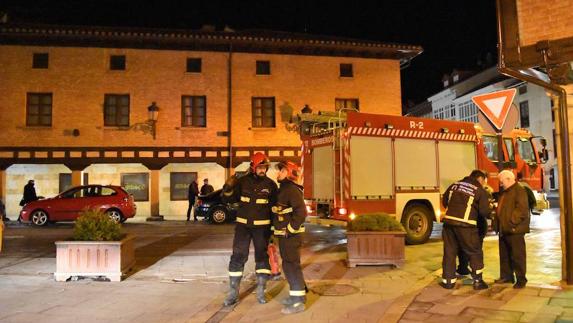 Algunos bomberos voluntarios, ante el edificio incendiado. 