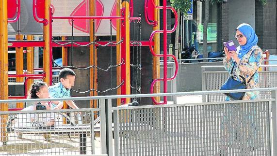 Una mujer musulmana observa a un par de niños de la misma nacionalidad. 