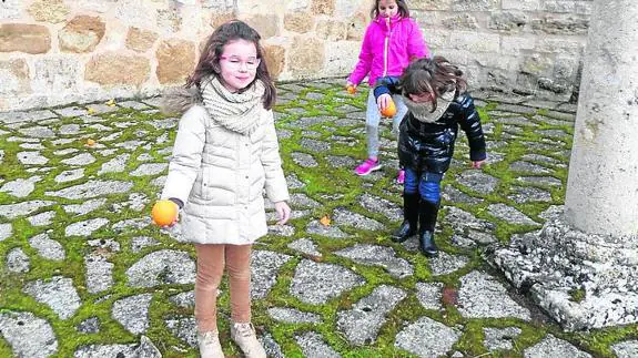 Los niños, durante el juego de rodar naranjas. 