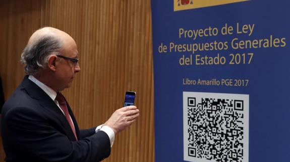 El ministro de Hacienda, Cristóbal Montoro, escanea con el móvil el código QR del proyecto de Ley de Presupuestos Generales del Estado. 