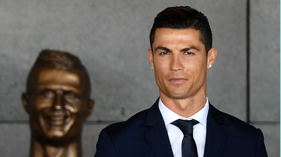 Cristiano Ronaldo, con su busto ubicado en el aeropuerto de Madeira detrás. 
