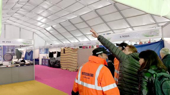 Uno de los expositores señala las roturas a un voluntario de Protección Civil.