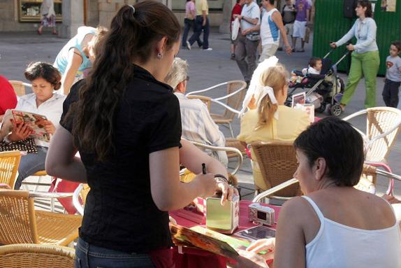 Una camarera atiende a los clientes en una terraza.