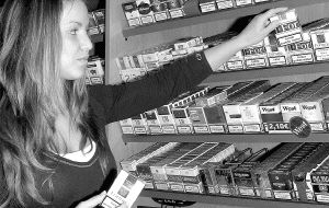 Una estanquera de Segovia coloca unos paquetes de tabaco en las estanterías. / ROSA BLANCO