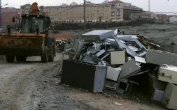 La excavadora que trabaja en esta operación especial pasa por el camino entre residuos y electrodomésticos viejos. / ANTONIO DE TORRE