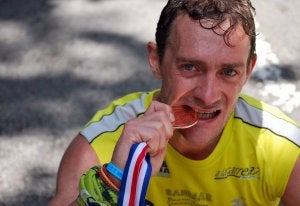 El atleta de La Granja-Valsaín-La Acebeda, Luis Alonso, muerde la medalla lograda./ EL NORTE