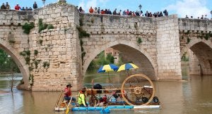 El público observa desde el puente medieval de Simancas cómo Daniel Roberts y Simon Desmet parten en balsa hacia Zamora. ::                             J. H.