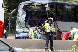 Un policía regula el tráfico delante del autobús de Palencia siniestrado. ::                             ÁNGEL DÍAZ-EFE