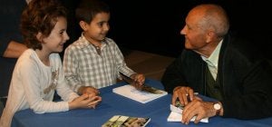 Isaías Rodrigo conversa con dos niños mientras les firma el libro recién presentado. ::
M. RICO