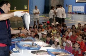 El pescadero Santiago Andrés enseña ayer los diferentes tipos de pescado a los niños participantes en el Día Thao.  ::
VÍCTOR HERRERO