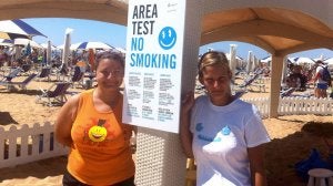 Unos turistas posan junto al cartel que anuncia la prohibición de fumar en esta zona del norte de la playa italiana.  ::
AFP