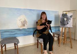 Eva Lorenzo Cebrián junto a su gato y a su último encargo, un gran cuadro de Ítaca.