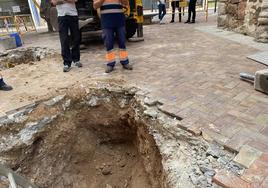 Operarios miran el agujero en el que han aparecido restos óseos.