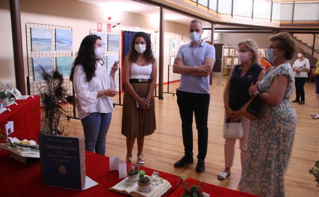 Imagen principal - Arriba; Eshter Cordero, responsable de la biblioteca, y Loli Orozco, profesora del taller, muestran al alcalde local Carlos Caro y a las concejalas Mercedes Pérez y Leticia Carrero la exposición. Debajo, algunos de los libros decorados. 