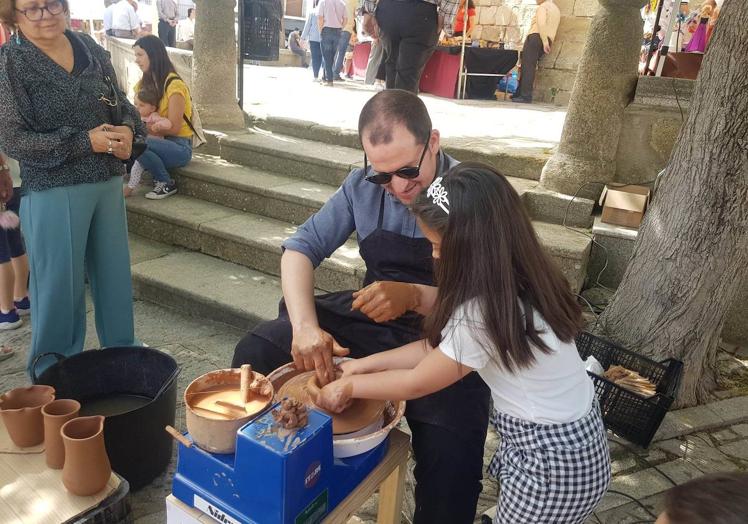 Imagen principal - Una niña en un taller de demostración de torno. Debao, uno de los puestos de alfarería de la feria.