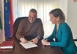 El alcalde, Carlos Caro, firmando el acuerdo con la directora de la Once en Cáceres, Isabel Góngora.