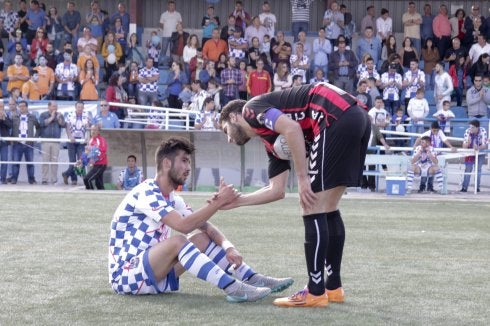 Un jugador del Azuqueca ayuda a incorporarse a Casado. 