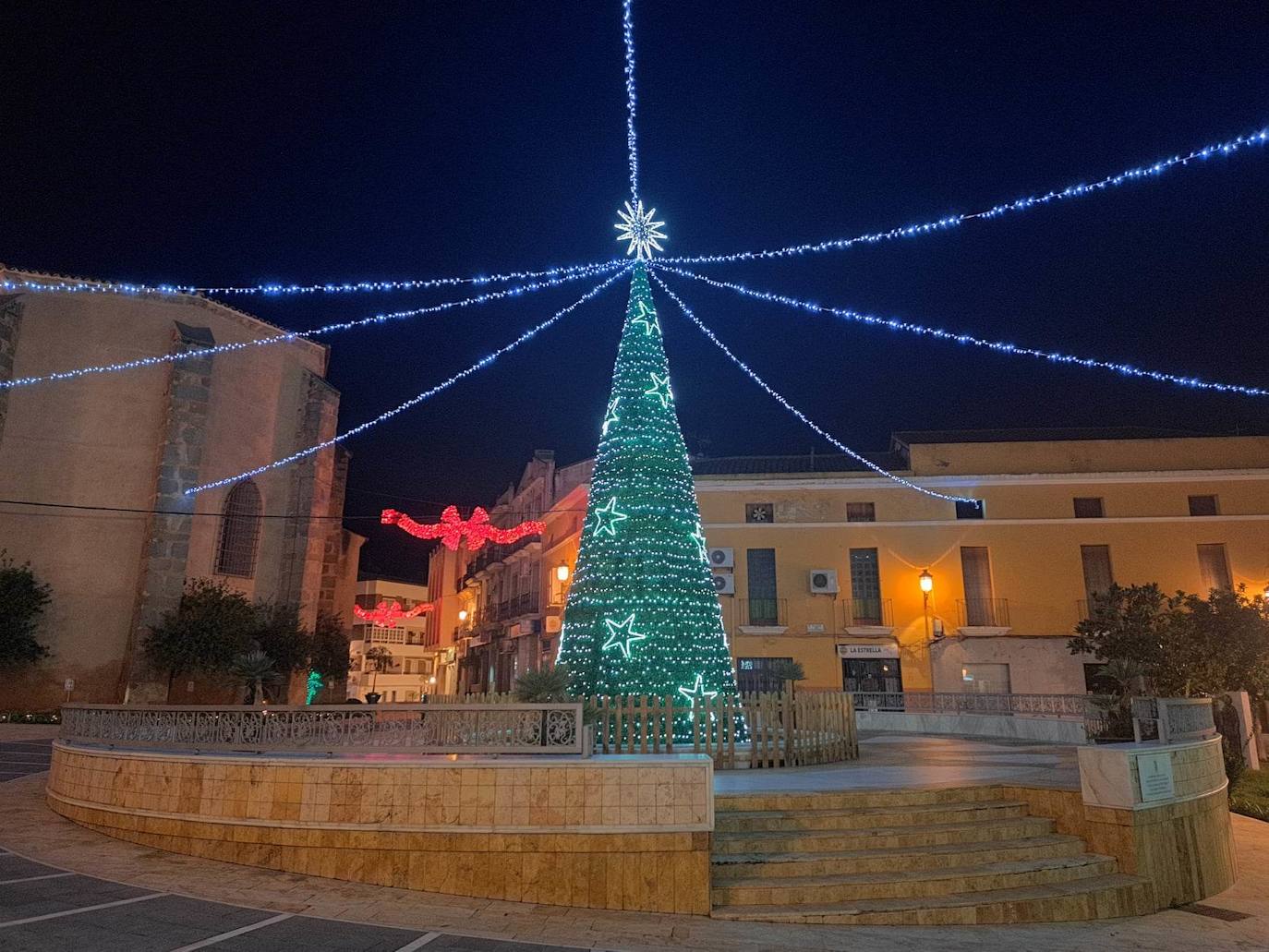 Campanario invita estos días a dar un paseo por sus calles contemplando las luces de colores y todos los motivos que marcan el camino. Pero, si hay algo que llama la atención del alumbrado navideño campanariense, es esa bonita postal desde la iglesia hasta la Plaza de España, donde espera un gran árbol de Navidad rodeado de guirnaldas de luces blancas. 