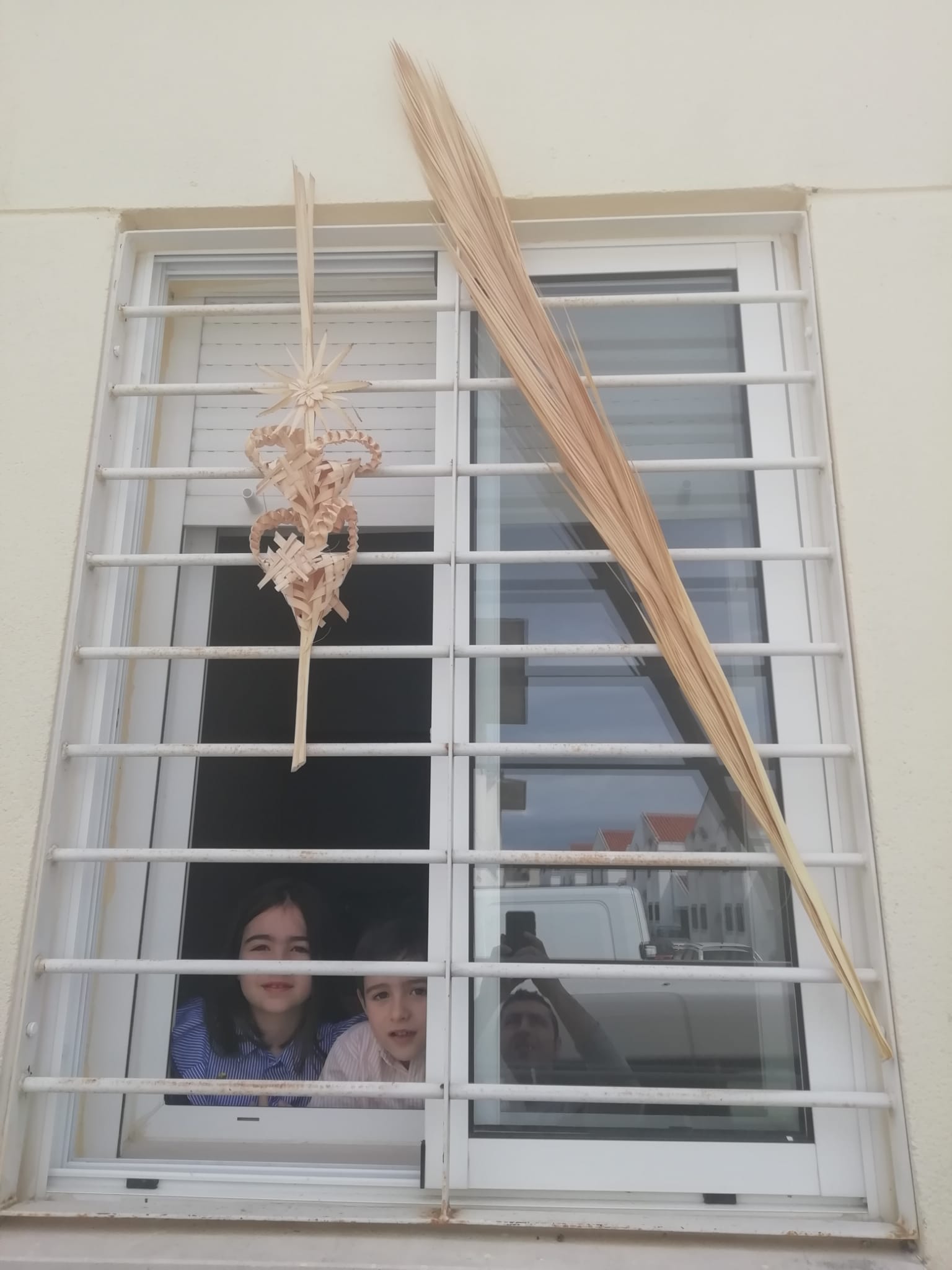 Imagen secundaria 2 - Contraste de imágenes de la celebración del pasado año, con la procesión de la Burrina, a la de este año, con niños sacando los ramos a sus ventanas, y la Policía entregándo algunos por los hogares. CEDIDAS